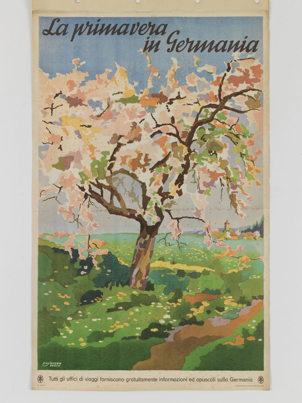 albero ed estesi prati fioriti sullo sfondo di un villaggio all'orizzonte (manifesto) di Glintzer Emmy (sec. XX)