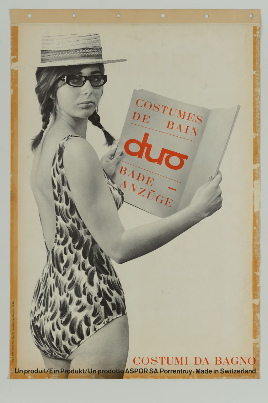 fotografia di donna in costume da bagno con cappello di paglia e occhiali dà le spalle, voltandosi, mentre apre un foglio che publicizzail costumi da bagno duo (manifesto) di Jacques Stalder, Photo Moeschlin e Bauer - ambito svizzero (sec. XX)