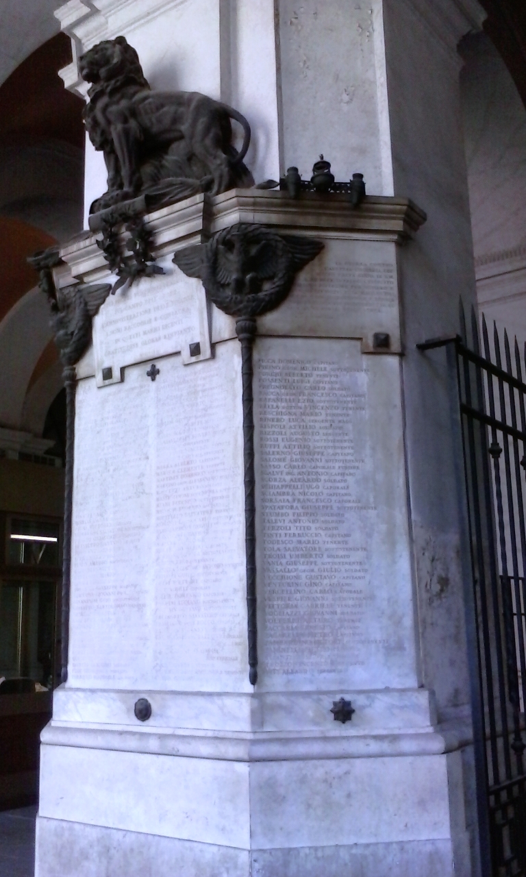 leone con le zampe poggianti su un volume delle Finanze (monumento ai caduti - a colonna) di Sindoni Turillo (sec. XX)