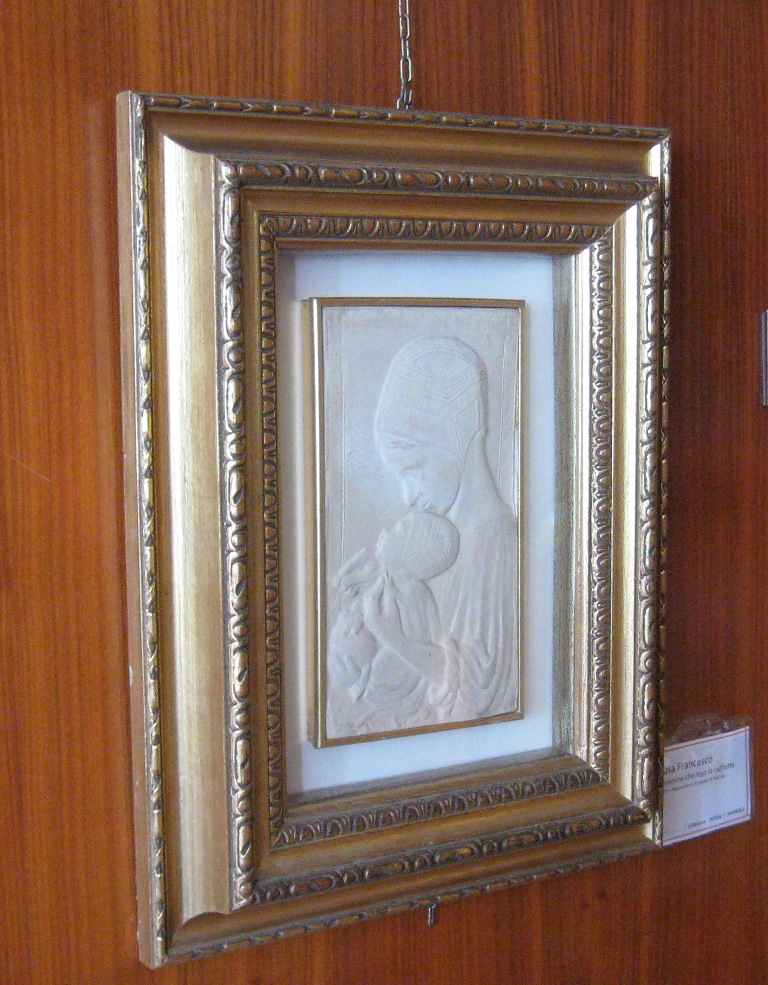 Mammina che lega la cuffietta, figura femminile con neonato (rilievo)