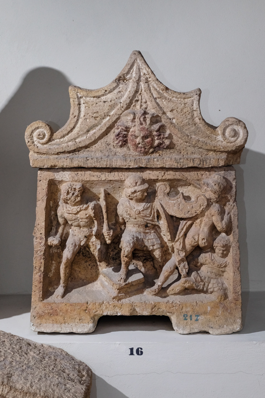 combattimento presso un altare (urna/ cineraria, cassa, con iscrizione, cubica, decorata) - bottega perugina (II a.C)