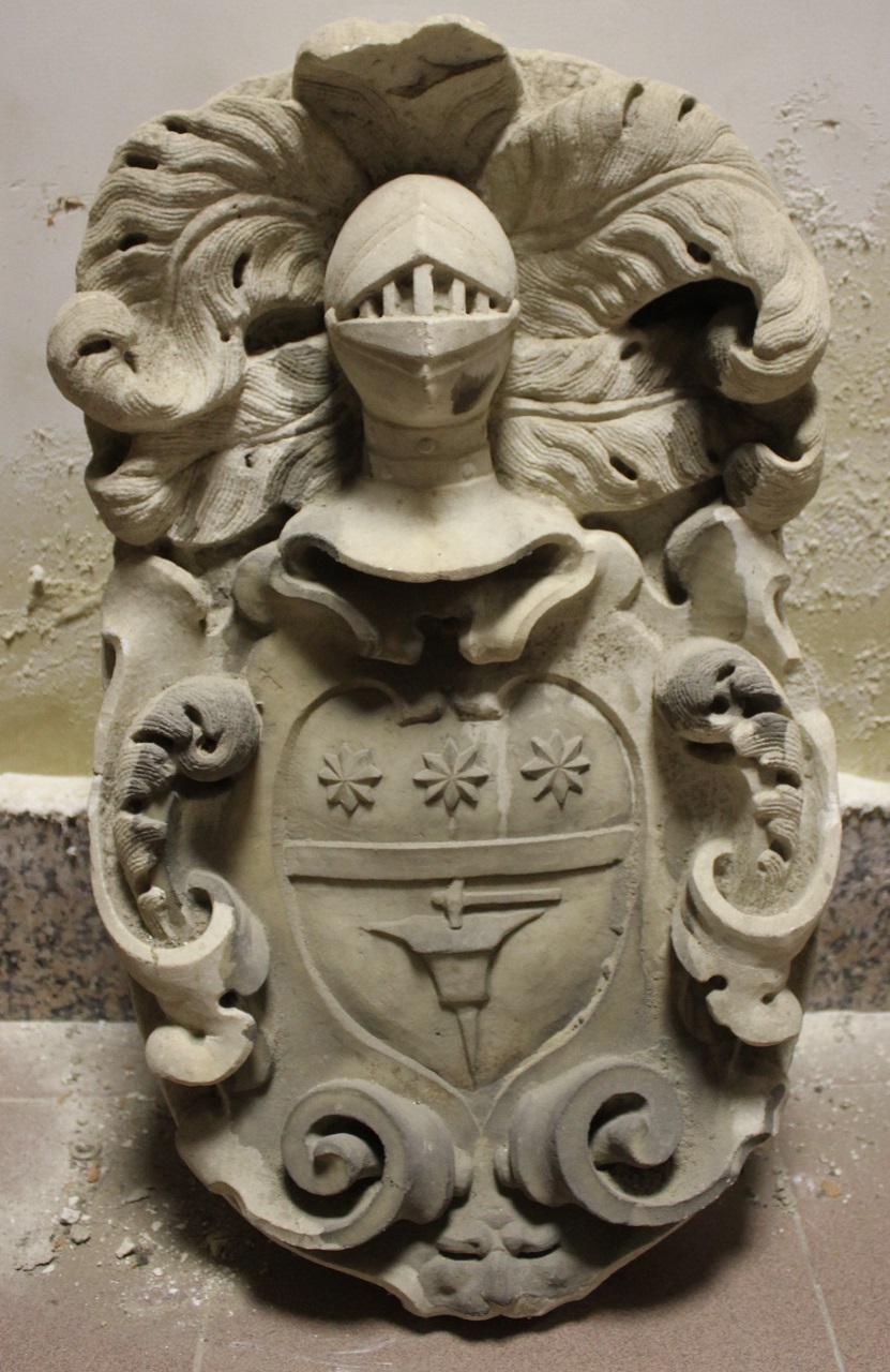 Scudo araldico figurato, sormontato da celata piumata e attorniato da volute a cartoccio (stemma nobiliare) - bottega messinese (XVII)