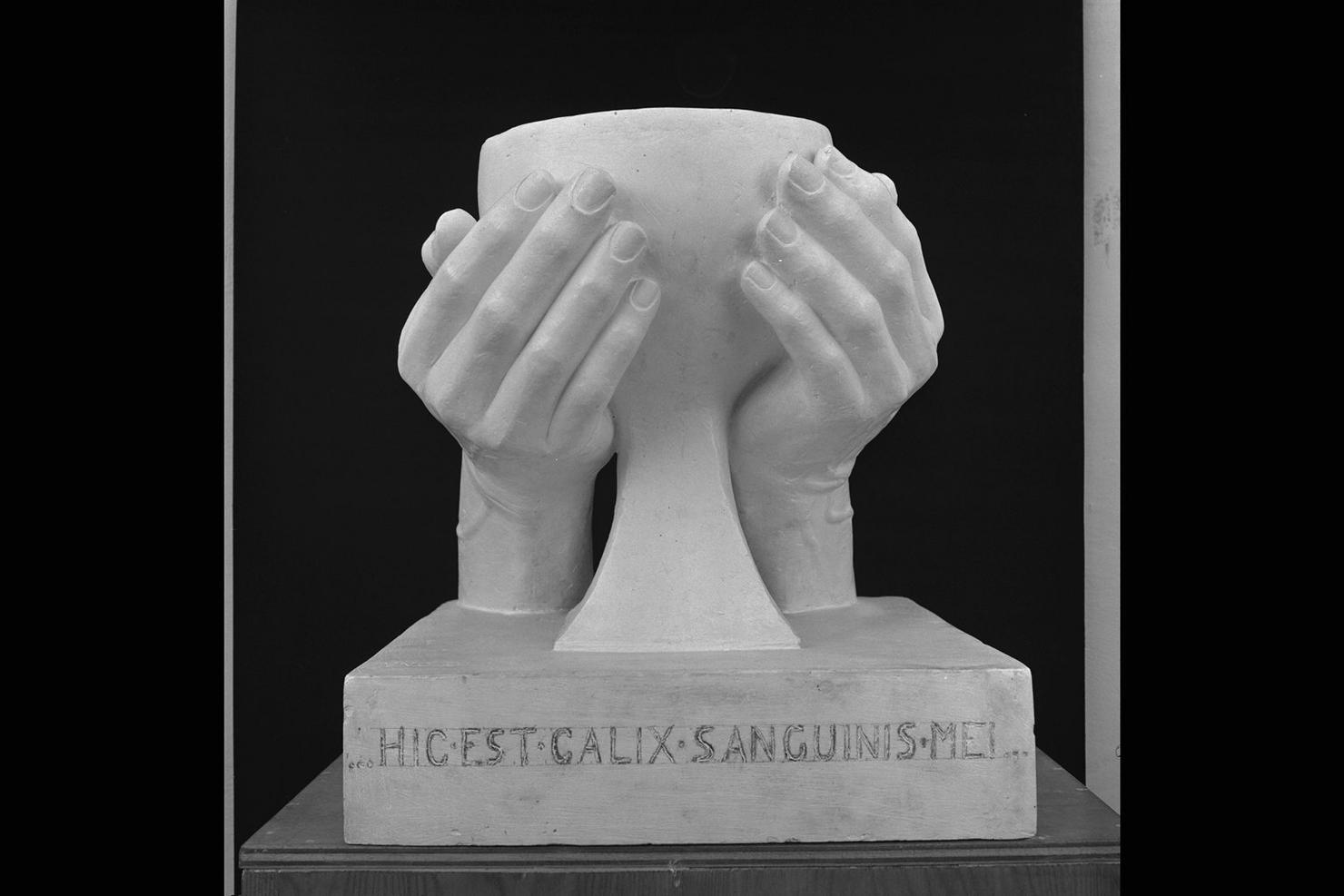Hic est calix sanguinis mei, calice stretto da mani (scultura) di Gera Uno (sec. XX)