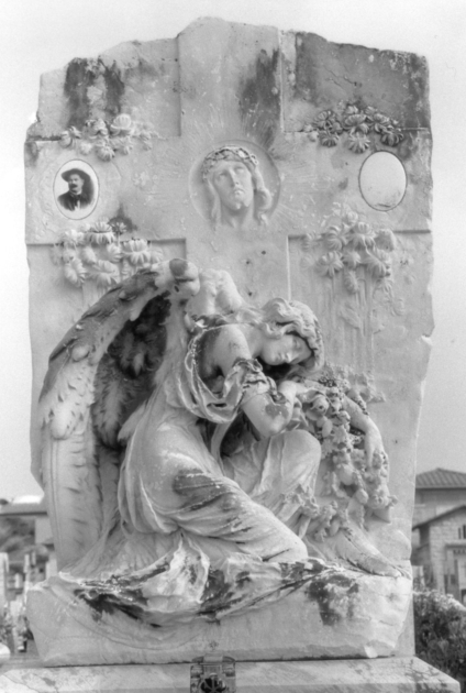 Angelo dolente con fascio di fiori inginocchiato ai piedi della croce sulla quale è scolpito il volto di Cristo (stele funeraria) di Arrighini Luca (sec. XX)