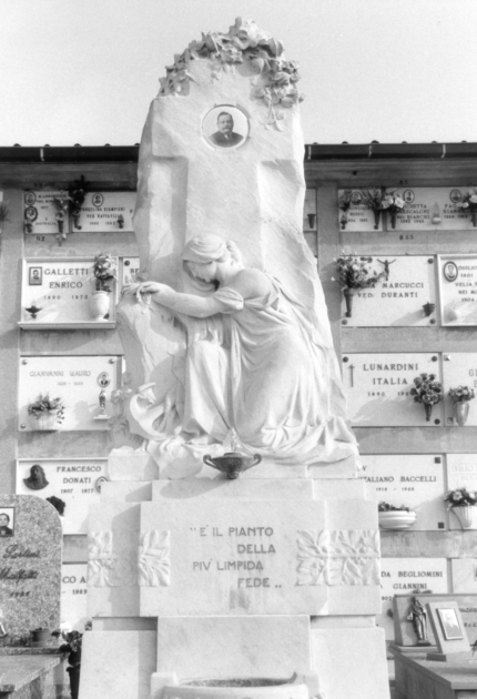 Figura allegorica femminile dolente inginocchiata ai piedi della croce (stele funeraria) di Zilocchi Giacomo (sec. XX)