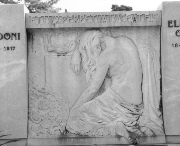 Figura allegorica femminile dolente inginocchiata raffigurata di spalle con lampada votiva (rilievo) - bottega apuo-versiliese (primo quarto sec. XX)