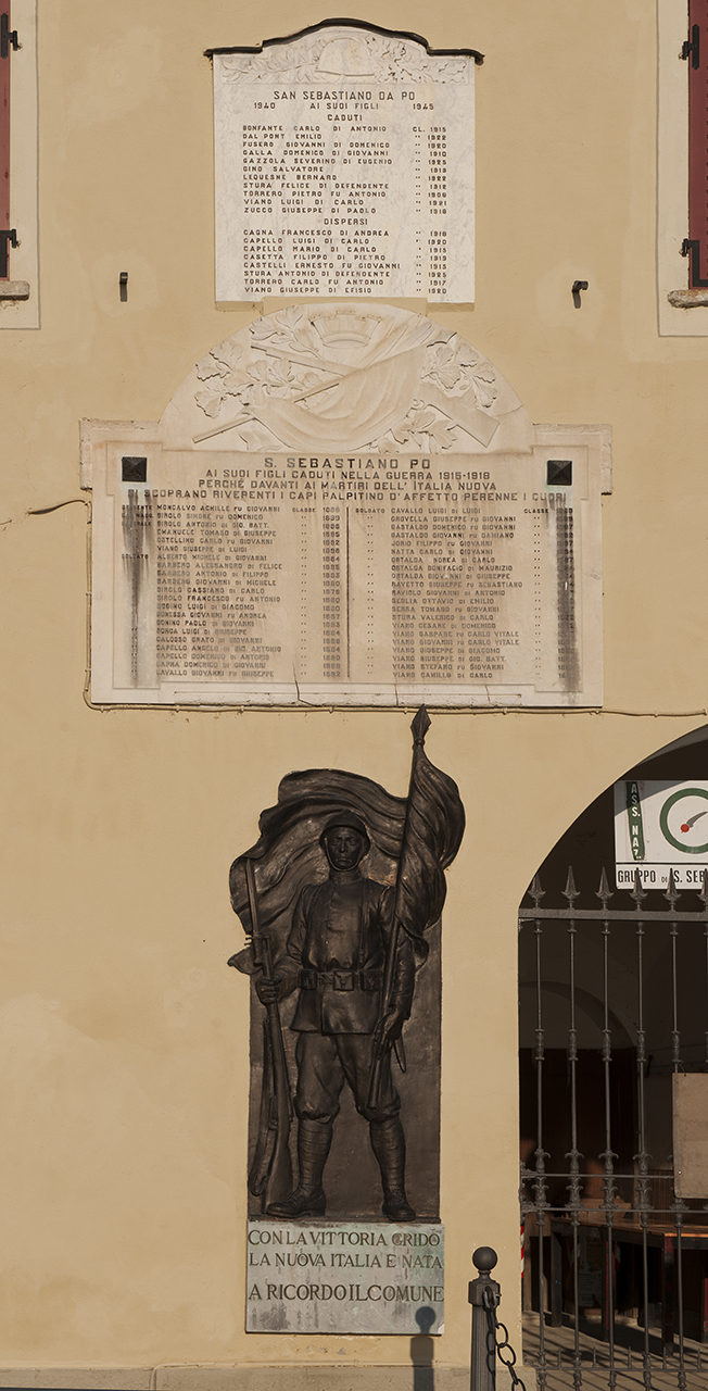 trofeo d'armi, figura di soldato che porta la bandiera (monumento ai caduti - a lapide) di Giuppone Battista (primo quarto sec. XX)