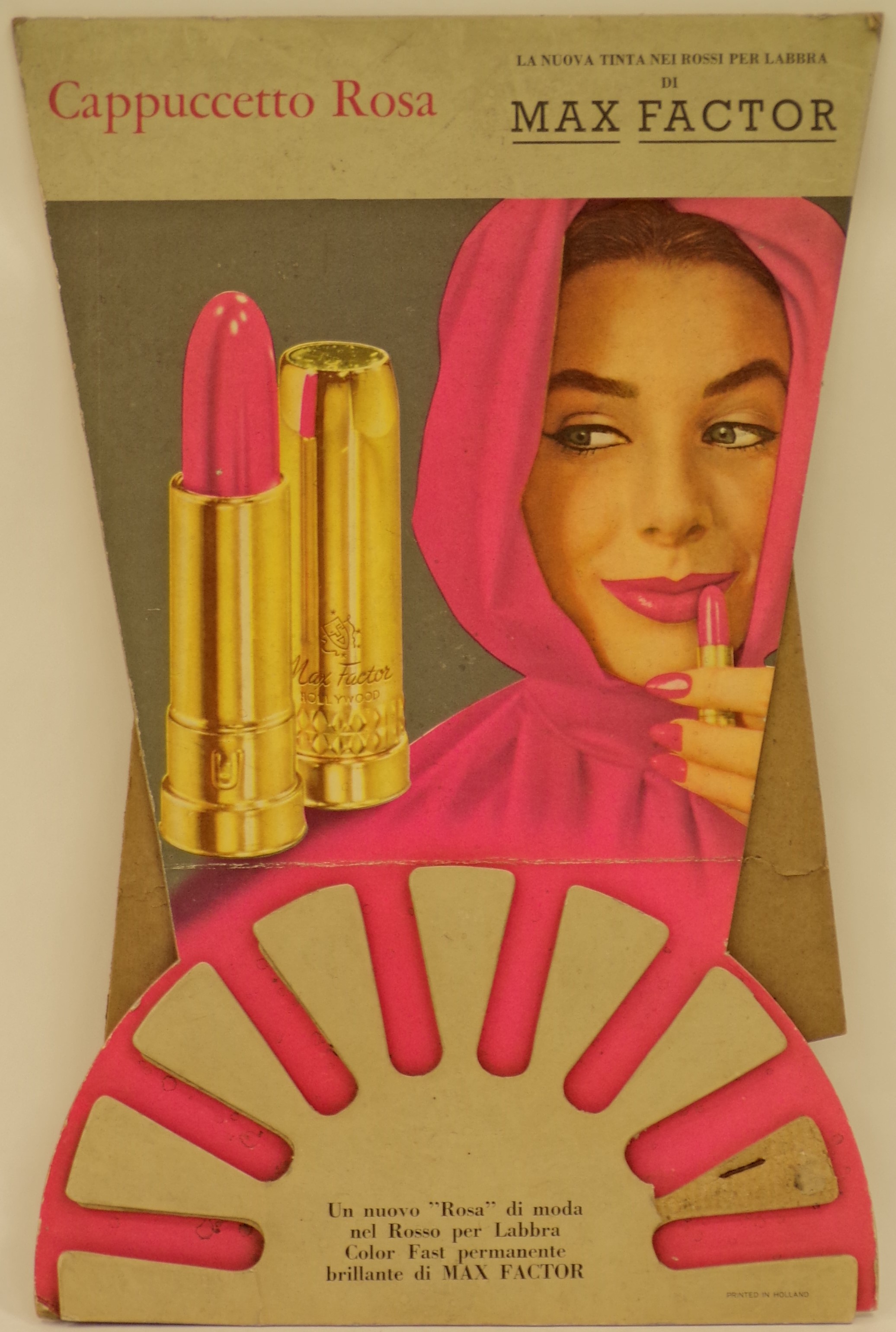 Cappuccetto Rosa la nuova tinta nei rossi per labbra di Max Factor, Ragazza con mantella e cappuccio rosa si colora di rosa le labbra guardando un rossetto Max Factor (Cartello) - ambito statunitense (terzo quarto XX)